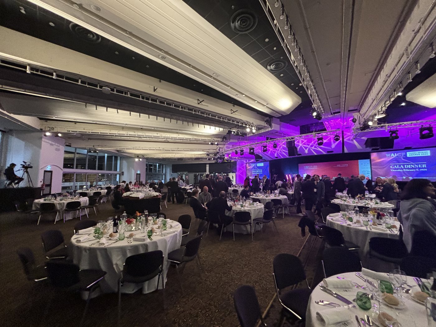 Dîner de gala avec tables rondes dressées et éclairage violet